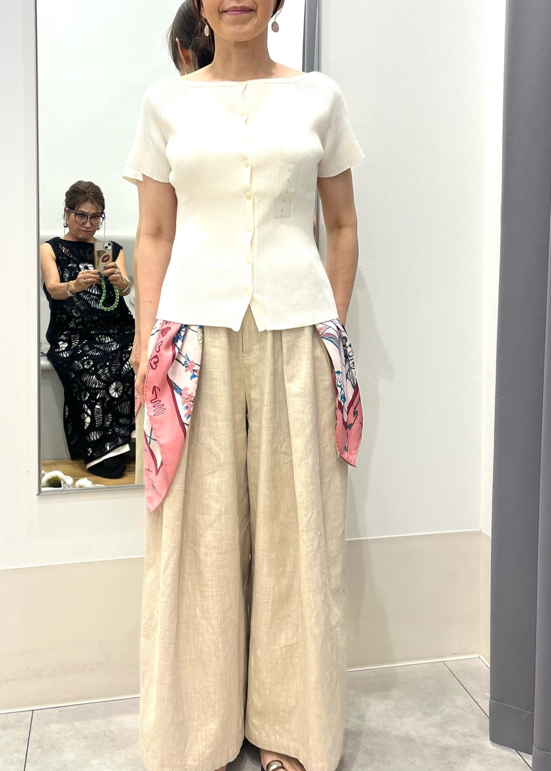 白トップスとベージュワイドパンツにピンクのスカーフを合わせた装い