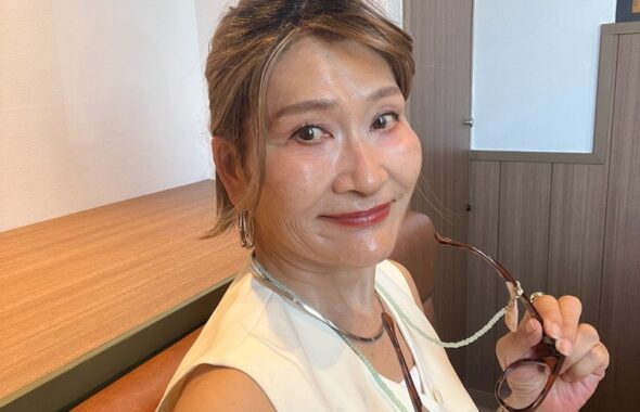 白いトップスに白いジレと茶系の眼鏡を合わせた上半身の着こなし
