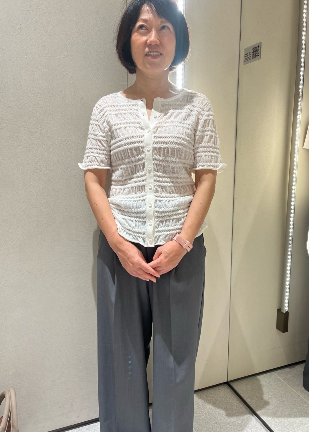 白い立体感のあるトップスとグレーのワイドパンツ