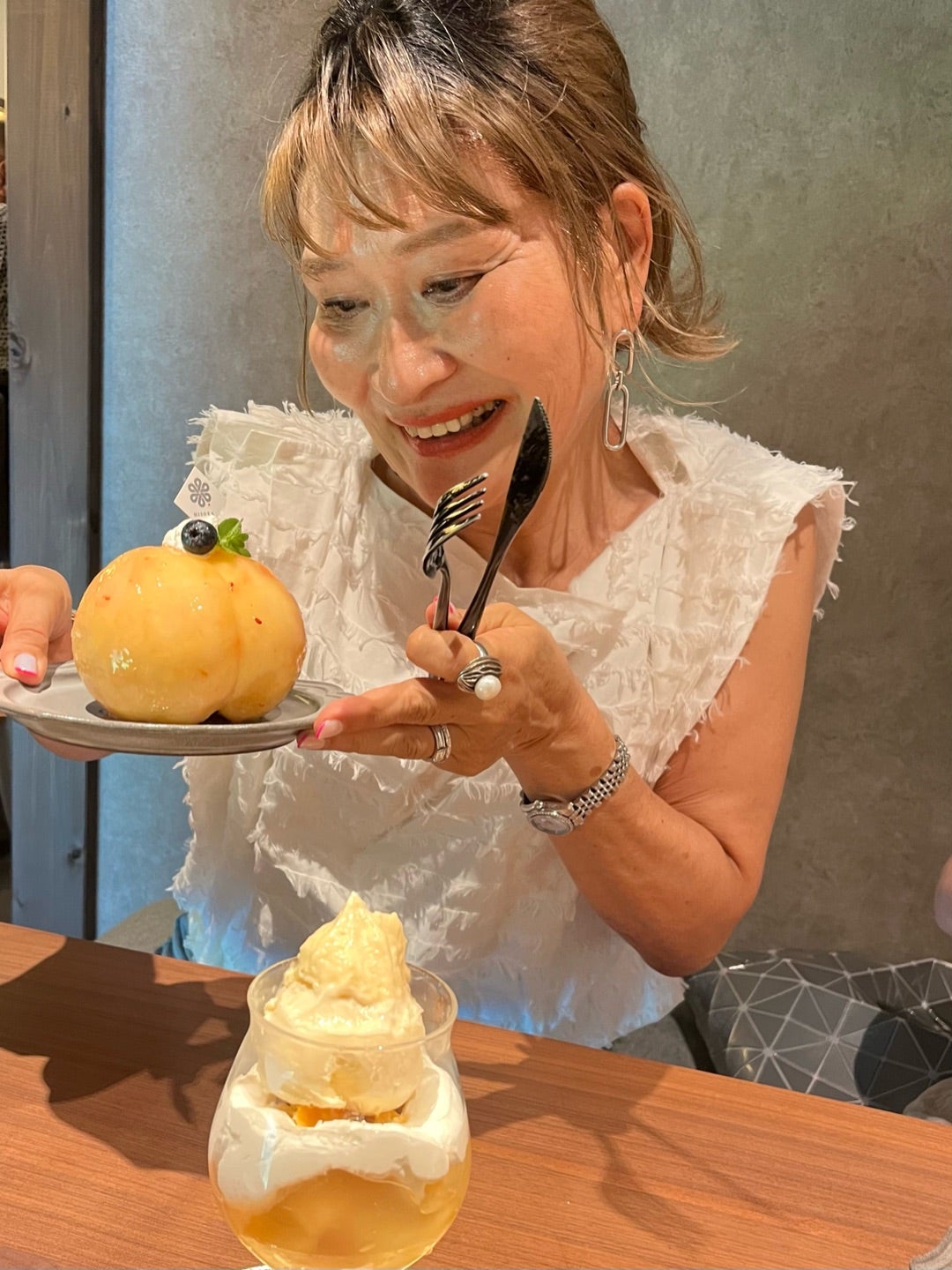 桃とフォークを手に笑顔を見せる三村由香