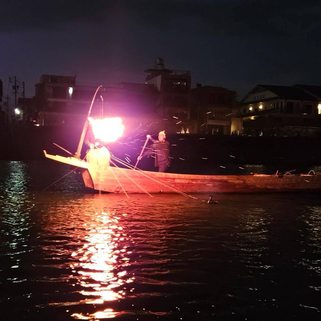 篝火を掲げた鵜舟が長良川を進む夜の光景