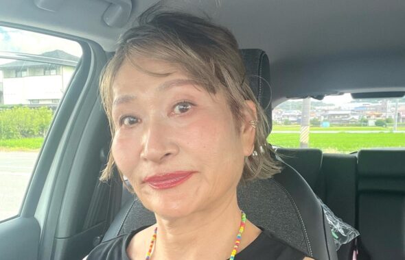 黒いトップス姿で車内にいる三村由香