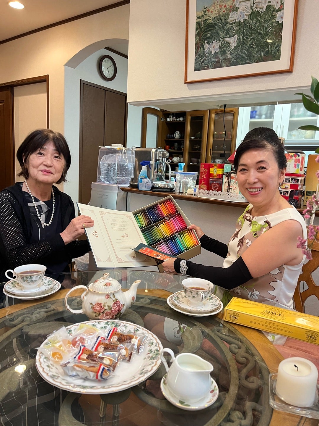 ティーカップを並べたテーブルで紅茶を手にする二人の女性