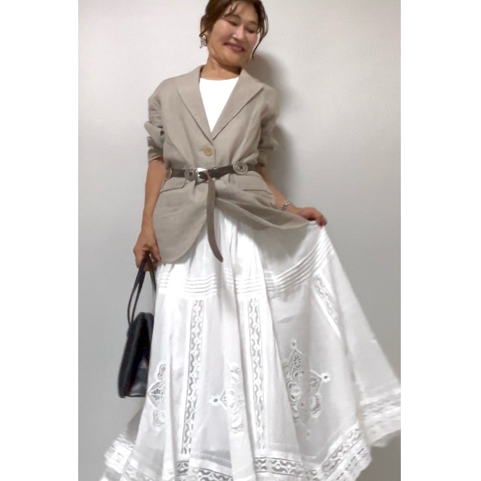 グレージュのジャケットと白いロングスカートを合わせた晩夏の装い