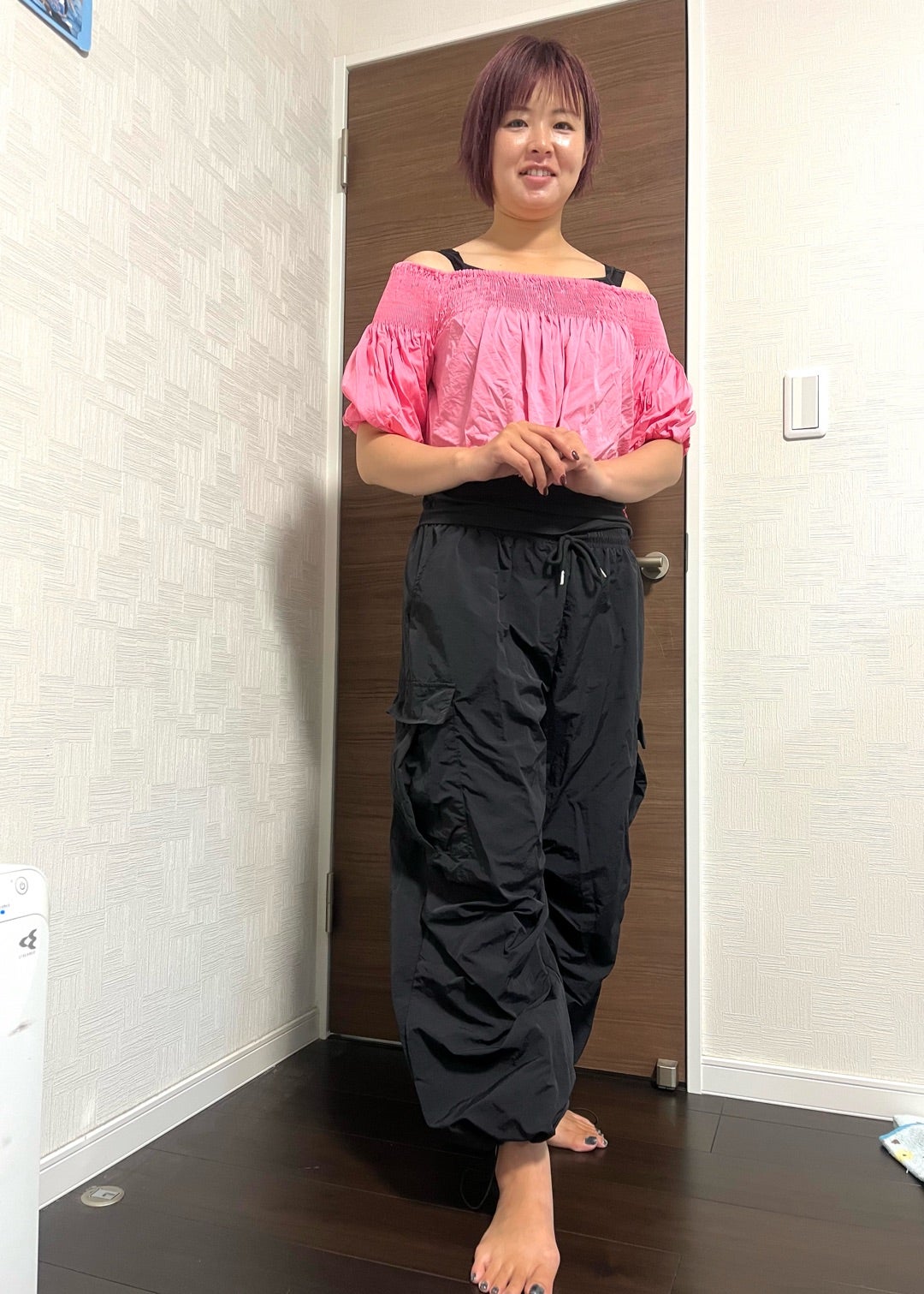 鮮やかなピンクの夏トップスを黒いボリュームパンツに合わせたコーデ