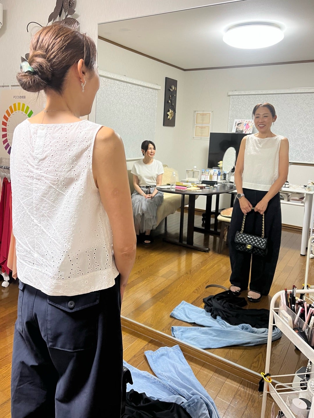 鏡の前で手持ちのベルトと服の合わせ方を確認する女性たち