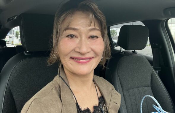 カーキと黒の装いに黒いレースを重ねて笑顔を見せる三村由香