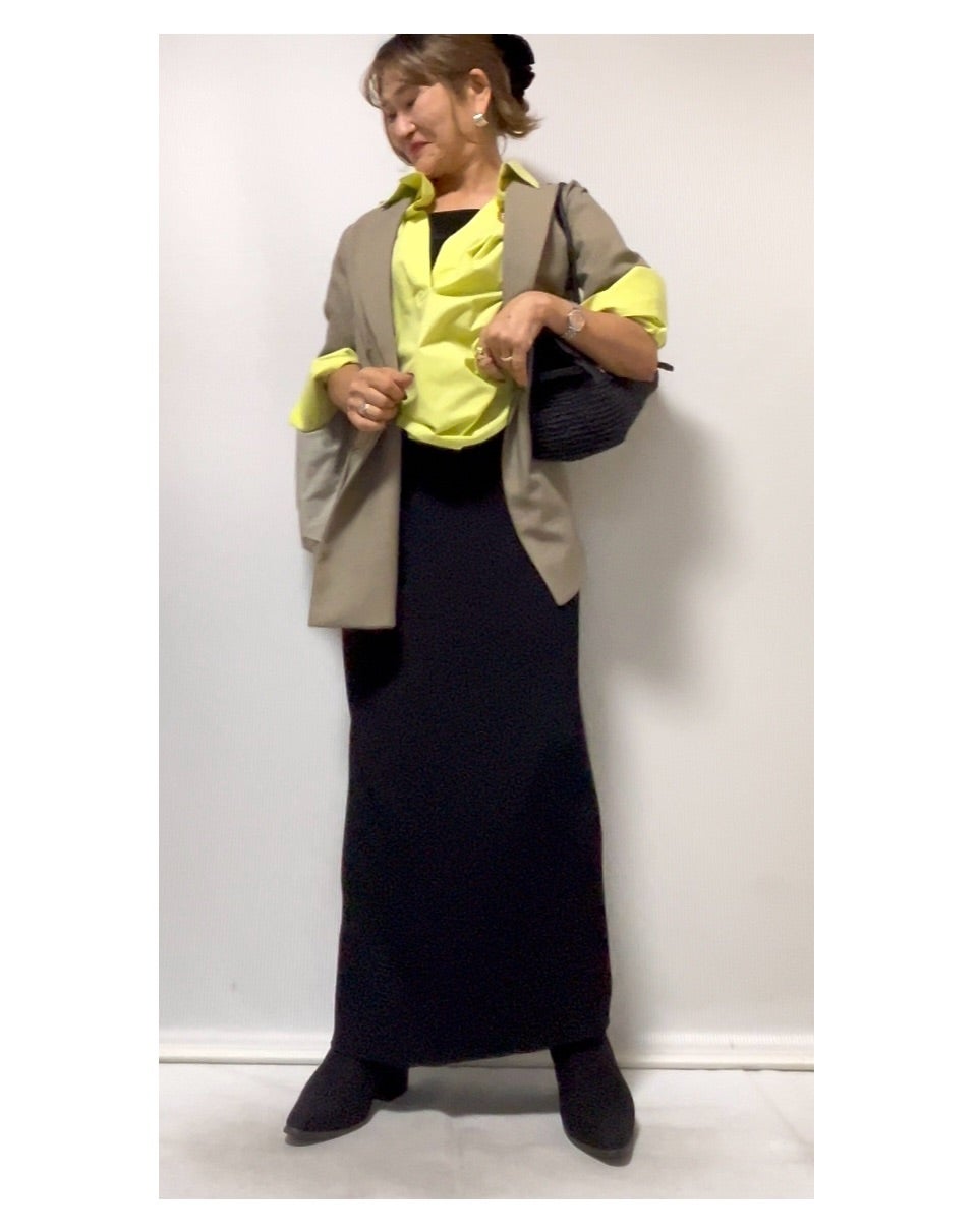 黒いバッグと靴でネオンイエローを引き締めたベージュジャケットの装い