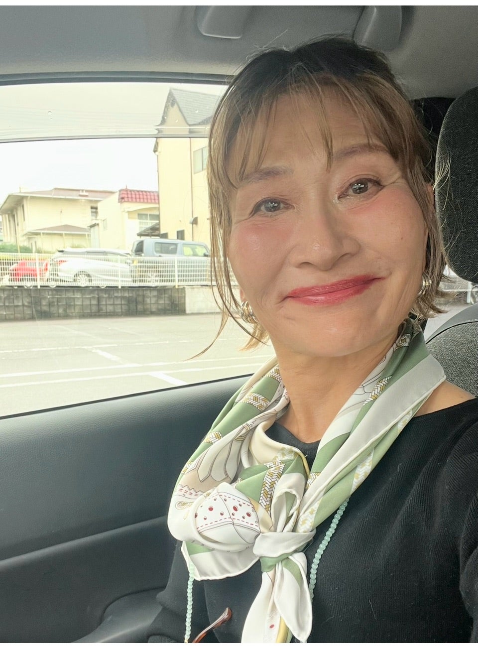 車内で首元にスカーフを巻いた三村由香