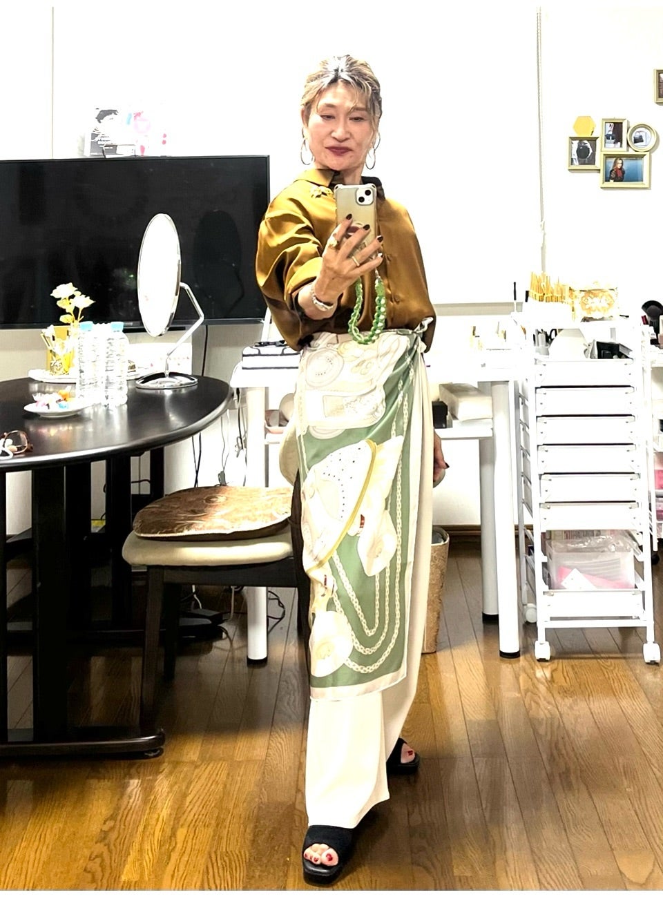 ブラウンと白の装いにグリーンのスカーフを合わせた三村由香