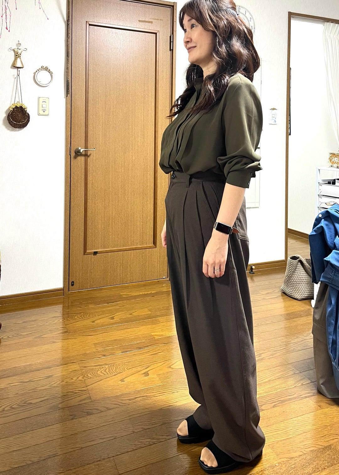 オリーブ色のブラウスとダークカラーのパンツを合わせた装い