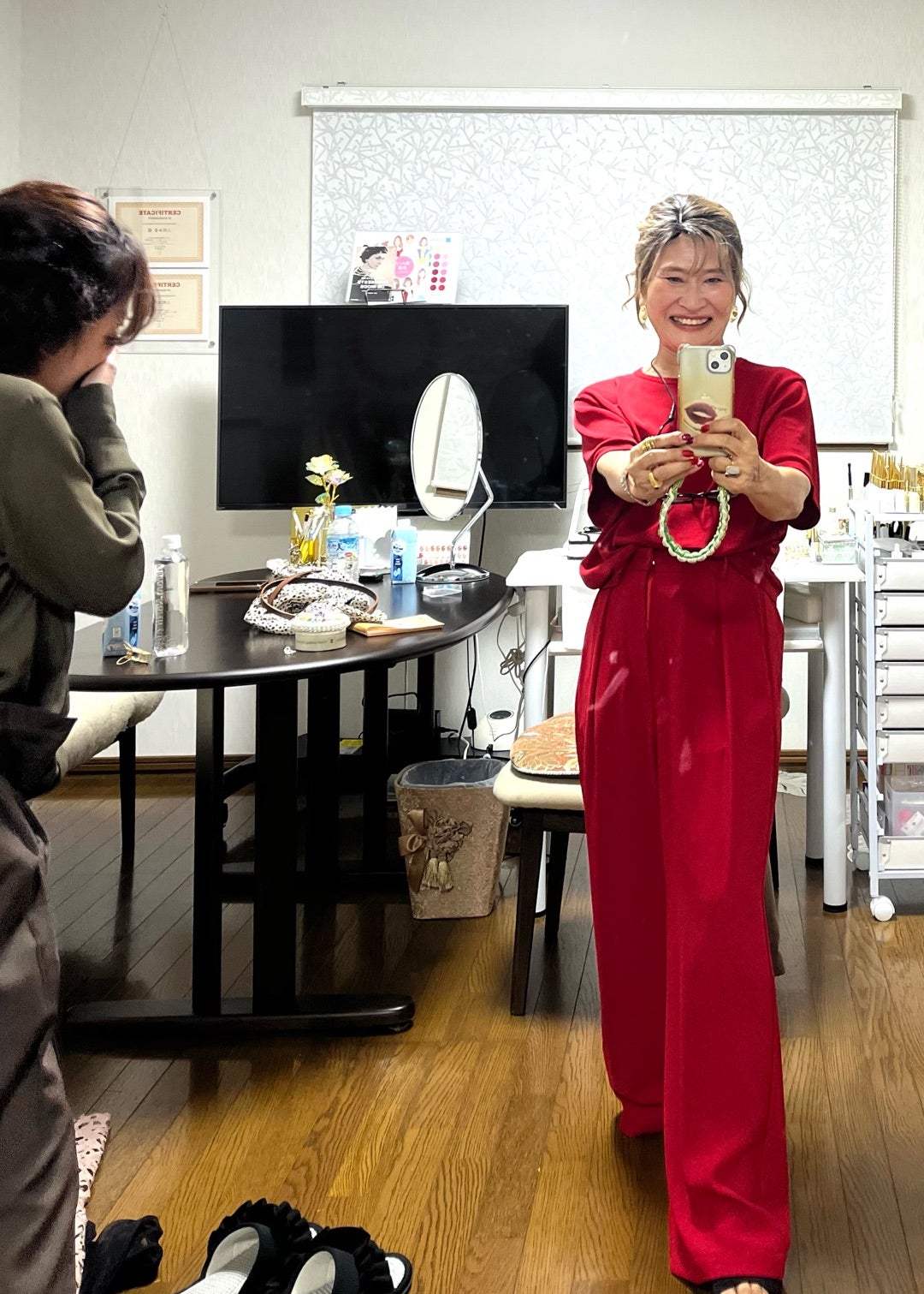 赤の装いでアクセサリーを手にする三村由香