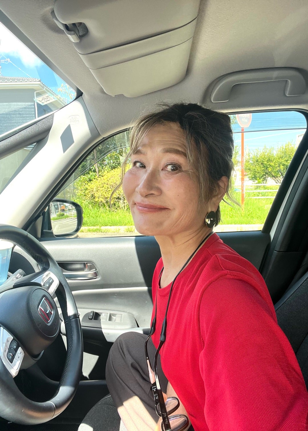 赤の装いで車内に座る三村由香