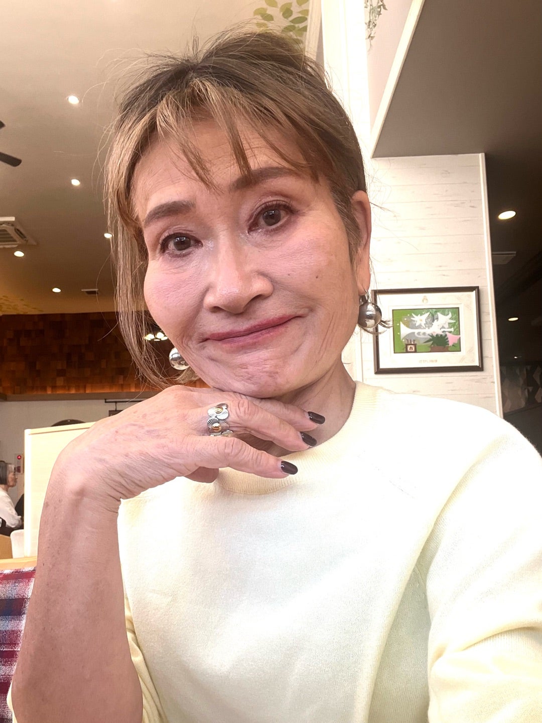 白いトップスを着て席に座る由香さん