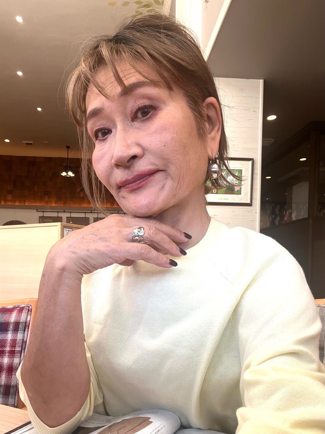 白いトップス姿で頬に手を添える由香さん