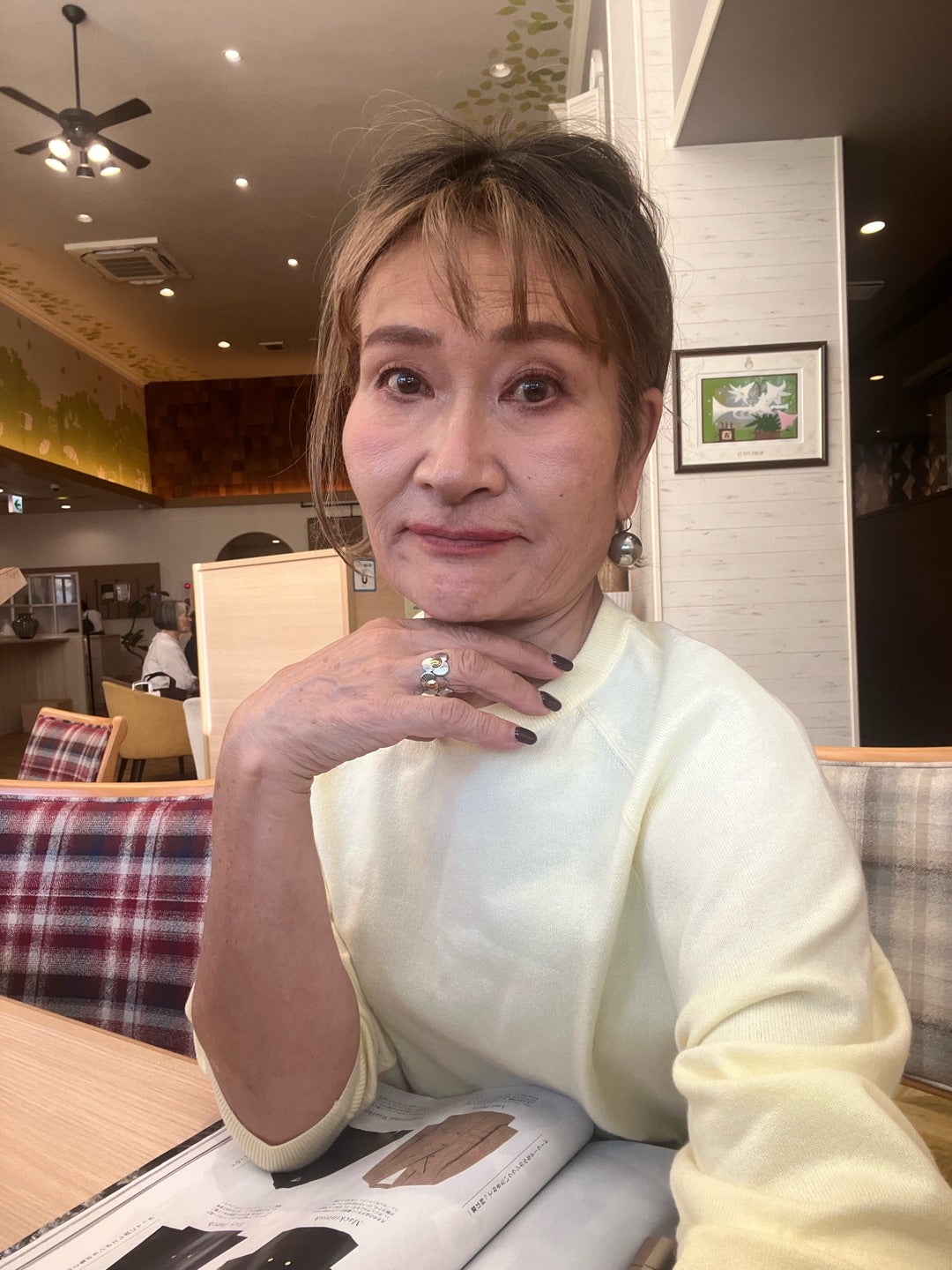 白いトップス姿でテーブルにつく由香さん