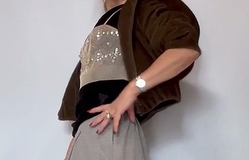 ブラウンの羽織りとグレーのパンツに、きらめくビスチェを重ねた着こなしのディテール