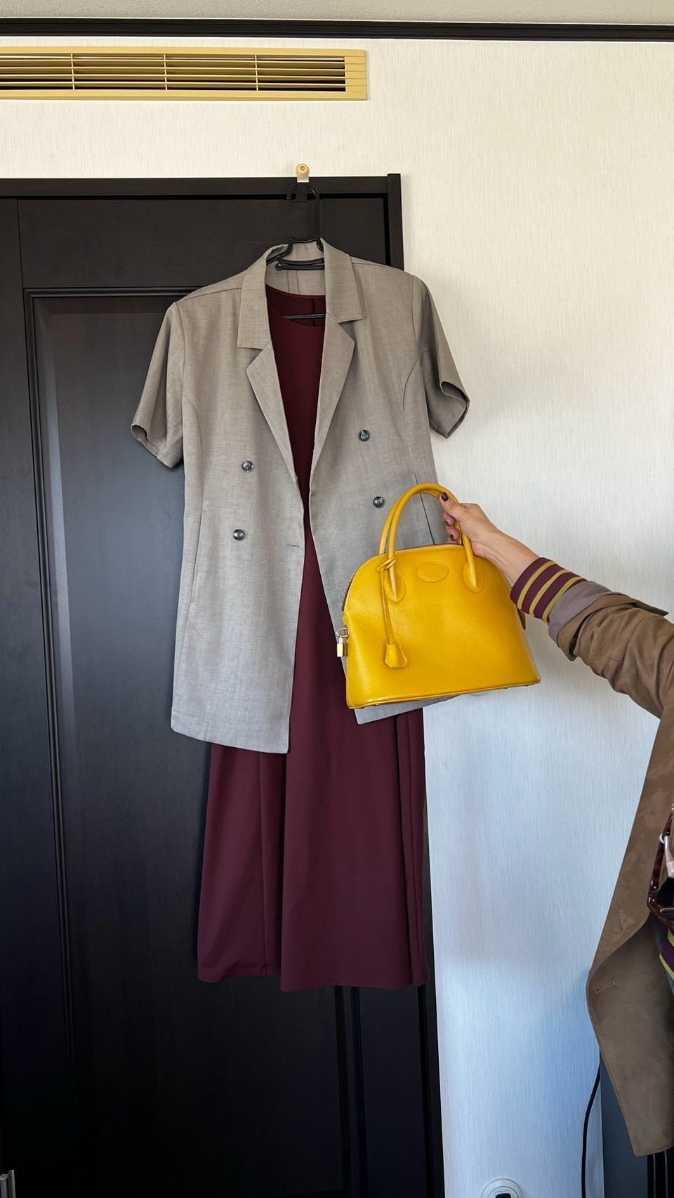 えんじ色の服とベーシックな羽織りに黄色いバッグを添える様子