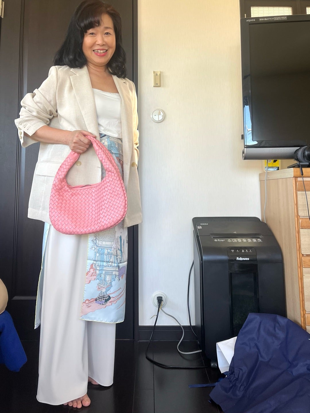 スカーフを腰に添え、ピンクのバッグを合わせた着こなし
